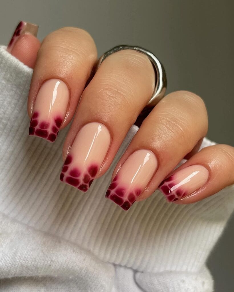 Nude nails with burgundy snake pattern French tip design