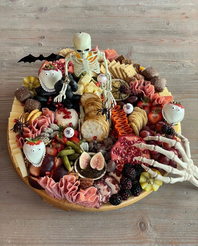 Halloween charcuterie board with skeleton decorations and strawberry ghosts