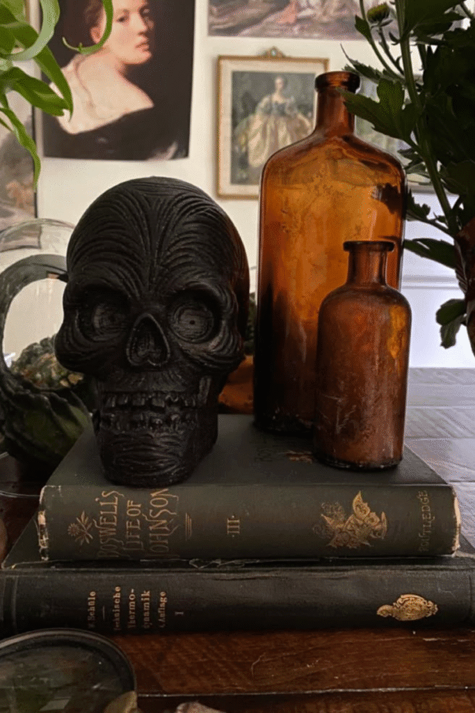 Black skull Halloween decor on vintage books with amber bottles