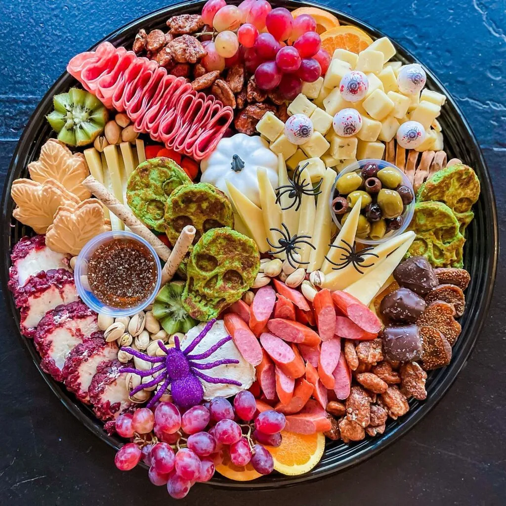 Halloween charcuterie board with green skull bites and purple spider