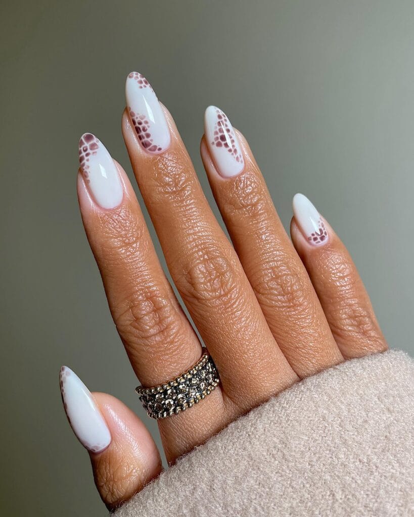 almond nails with milky white base and brown snake print accents, fall nail design