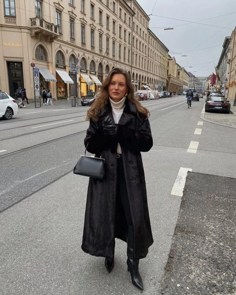 woman in long black coat and creamy turtleneck with gloves and boots, winter city outfit