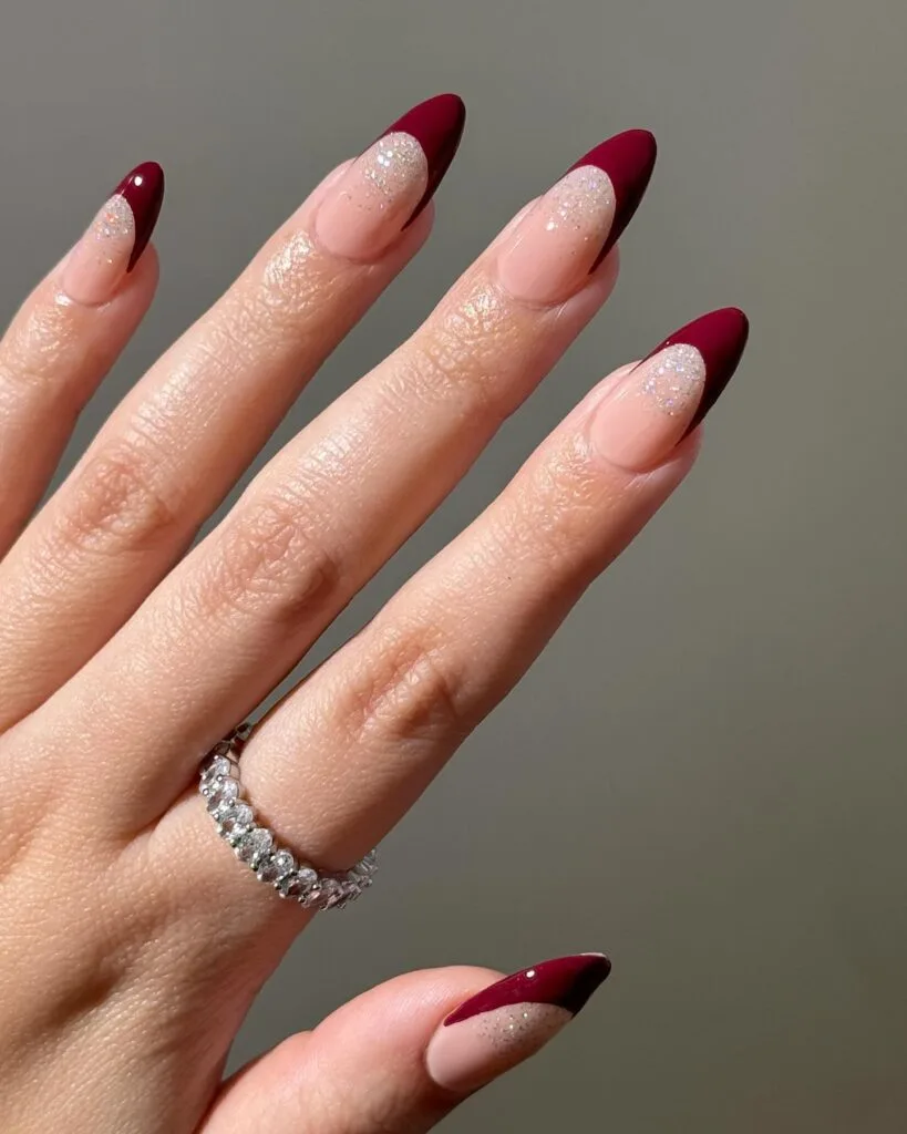 Deep berry French tips with glitter on almond nails" winter nail trends, frosted French