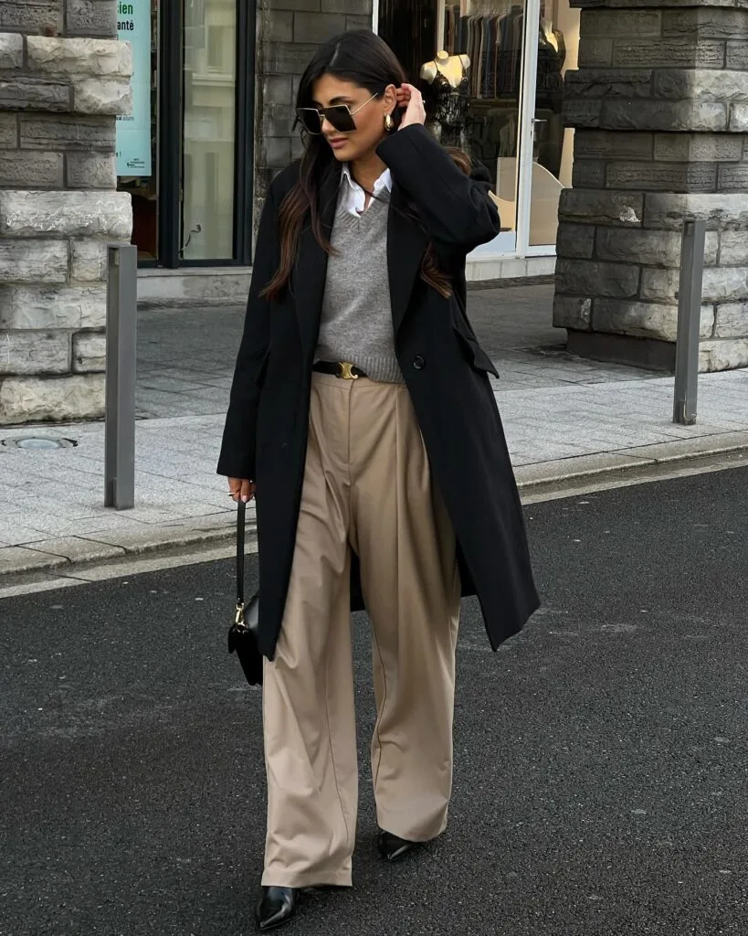 winter work outfit with black coat, grey sweater vest, white shirt, beige wide-leg trousers, black heels
