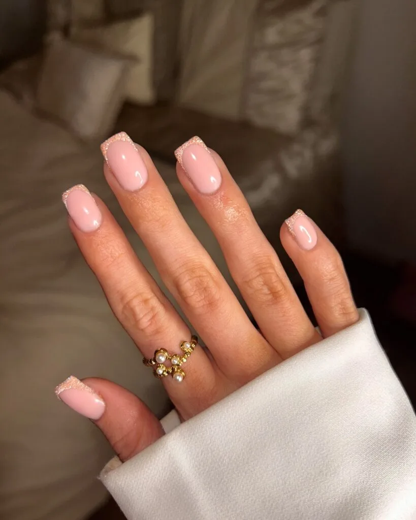 Soft pink French tips with shimmer on short nails" winter nail trends, subtle frosted look