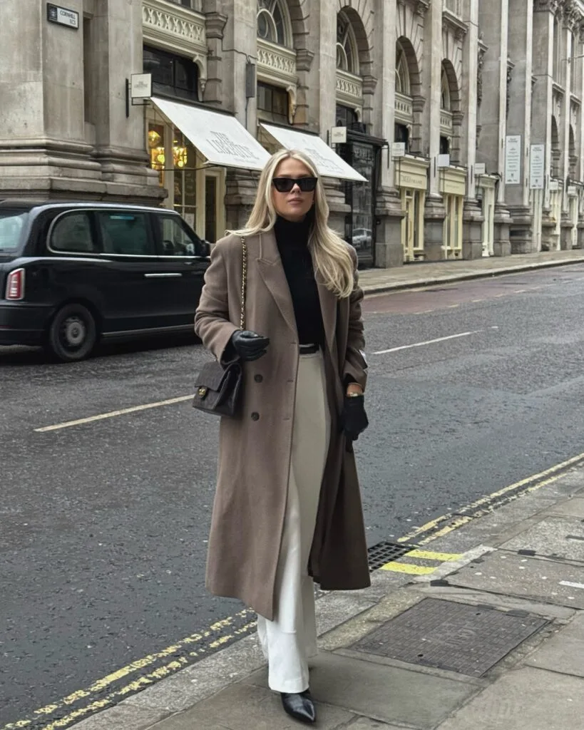 winter work outfit with taupe long coat, black turtleneck, white trousers, black gloves, chain bag, pointed shoes
