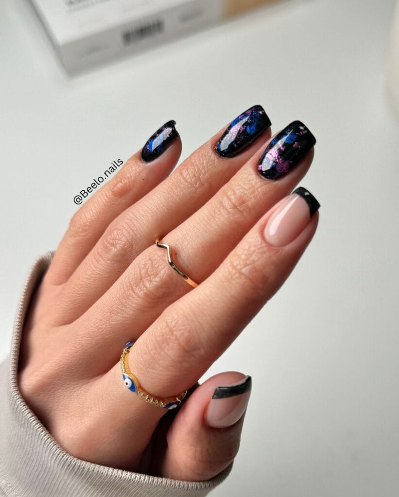 January nails with black galaxy shimmer nails and nude base with glossy black French tips.
