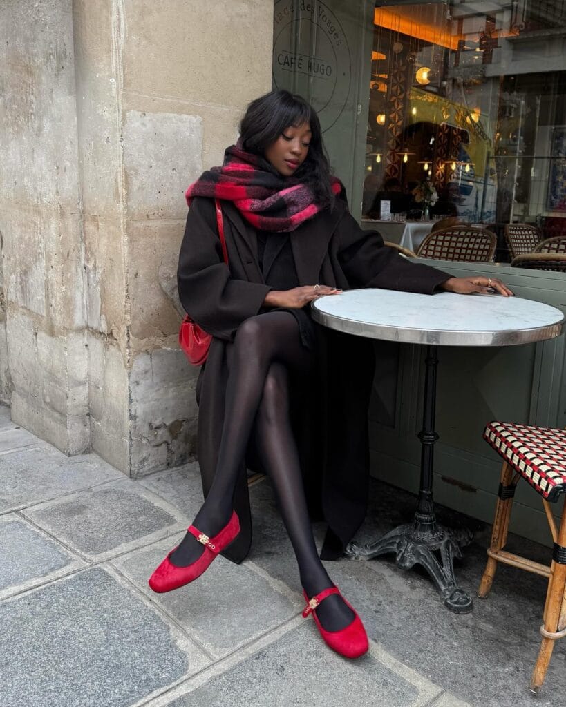 winter paris outfit with chocolate coat, plaid scarf, black dress, and red ballet flats