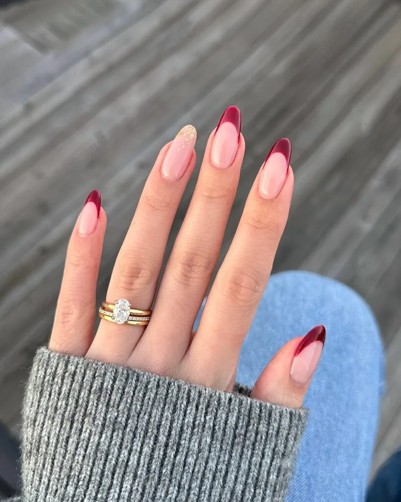 nude nails and deep burgundy French tips plus gold foil accent; simple winter nails.