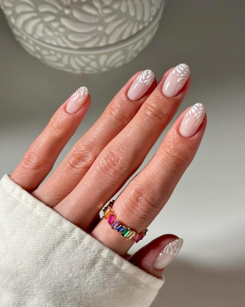 nude pink nails and white leaf-pattern tips; simple winter nails with delicate art.