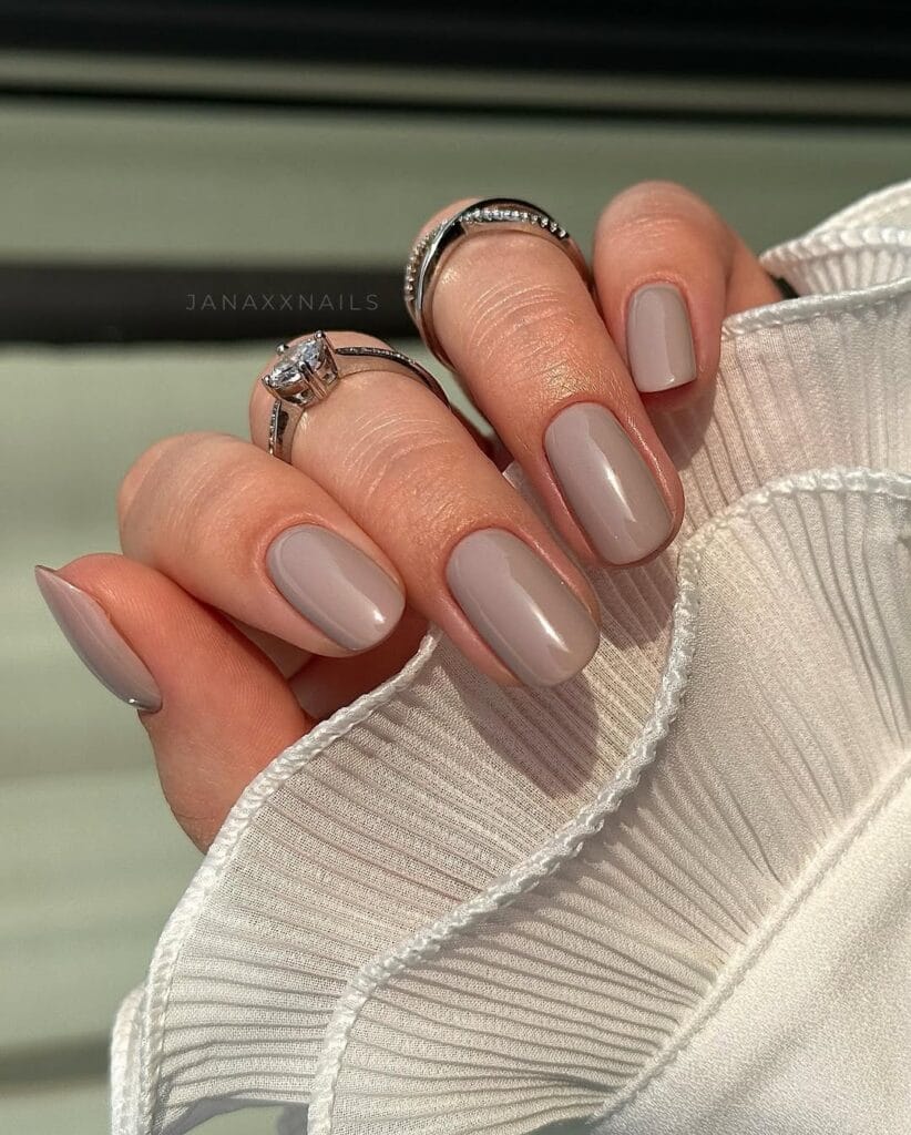 Glossy greige January nails on short oval nails with a clean minimalist finish.
