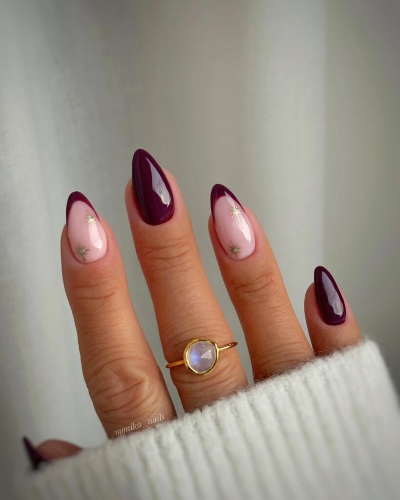 January nails with deep plum negative-space French and nude base, finished with tiny star gems.
