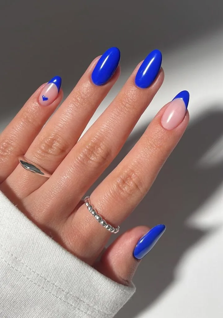 cobalt blue nails and blue French tips with a small heart detail; simple winter nails.