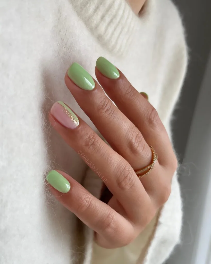 Glossy sage green and blush manicure with a thin gold stripe accent, simple winter nails.