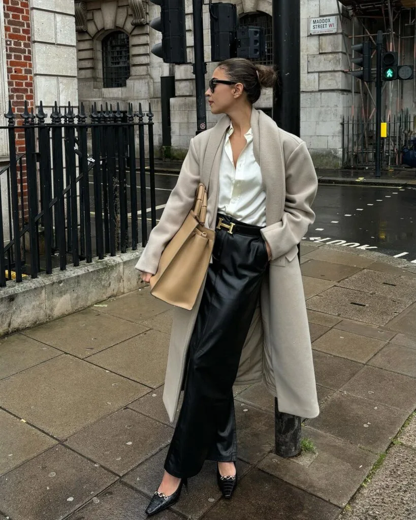 winter work outfit with beige coat, white blouse, black leather midi skirt, black flats, tan tote bag
