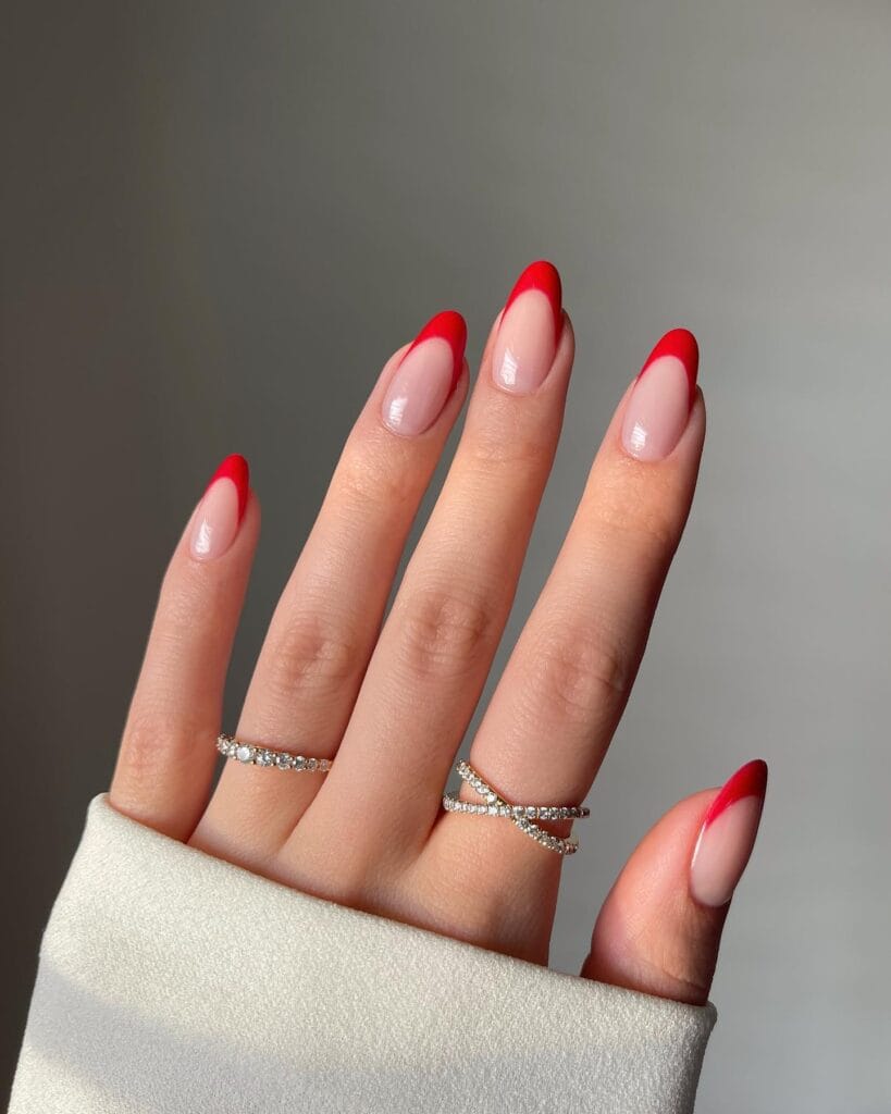 sheer nude nails with curved red french tips, elegant winter old money nails
