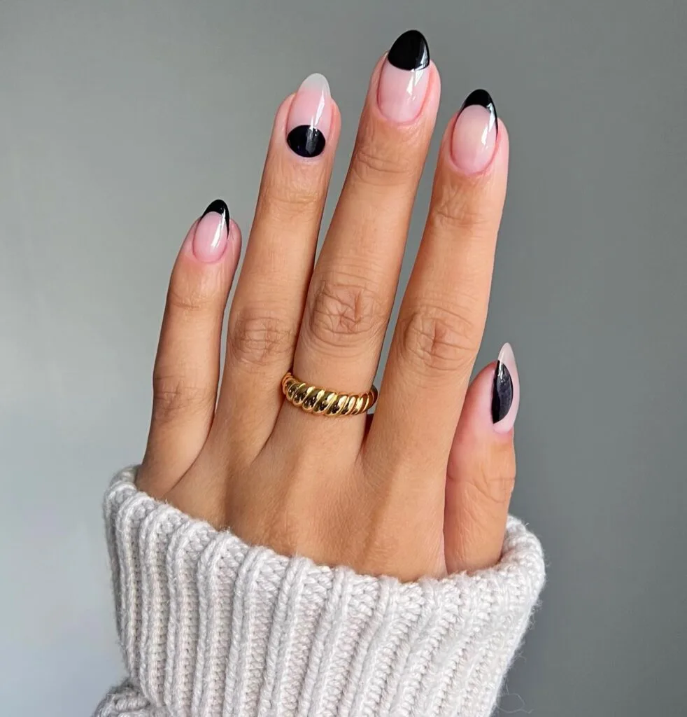 Sheer nude manicure with glossy black crescent and angled French tips, simple winter nails.