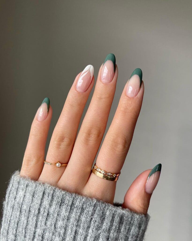 January nails with dark green French tips on almond nails over a nude base.

