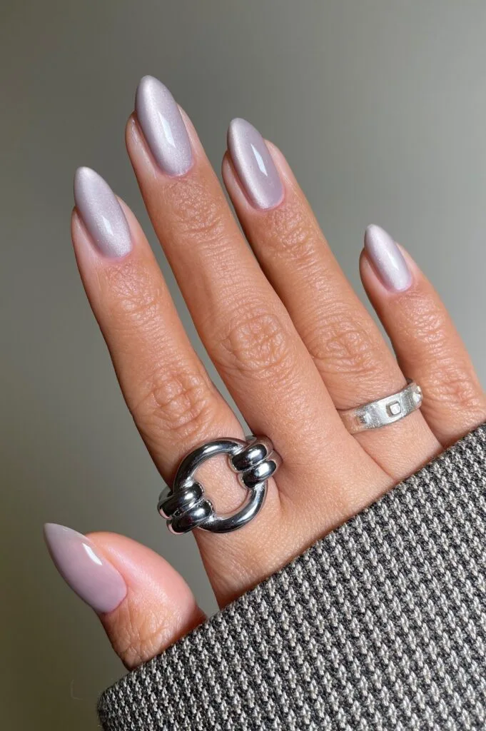Pearly chrome almond manicure in icy white-lilac sheen, simple winter nails.