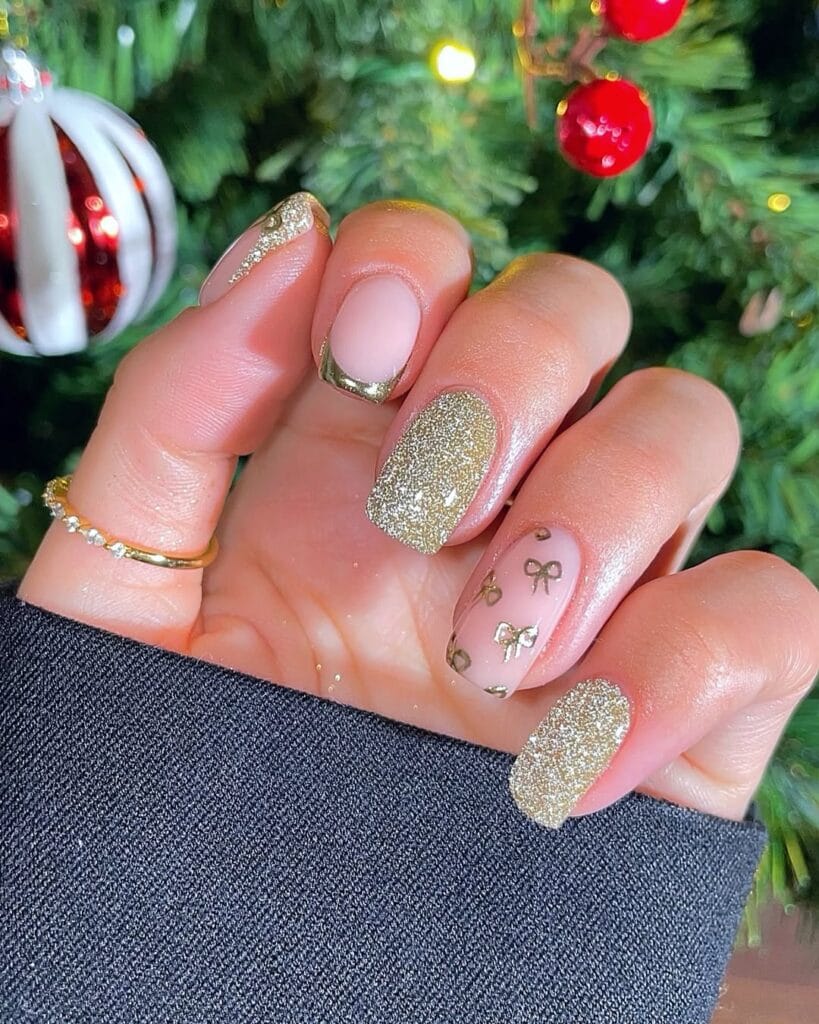 nude nails with gold French tips, gold glitter, and tiny gold bow art, Christmas nails