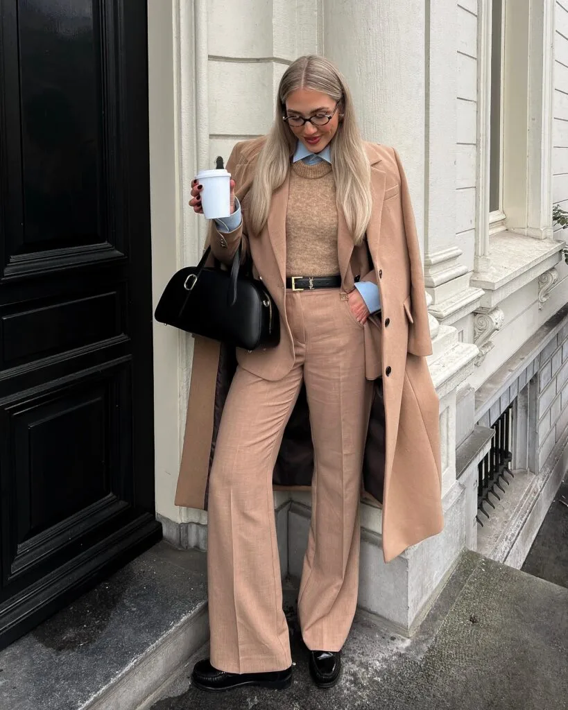 winter work outfit with camel blazer, matching wide-leg trousers, knit sweater layered over blue shirt, loafers
