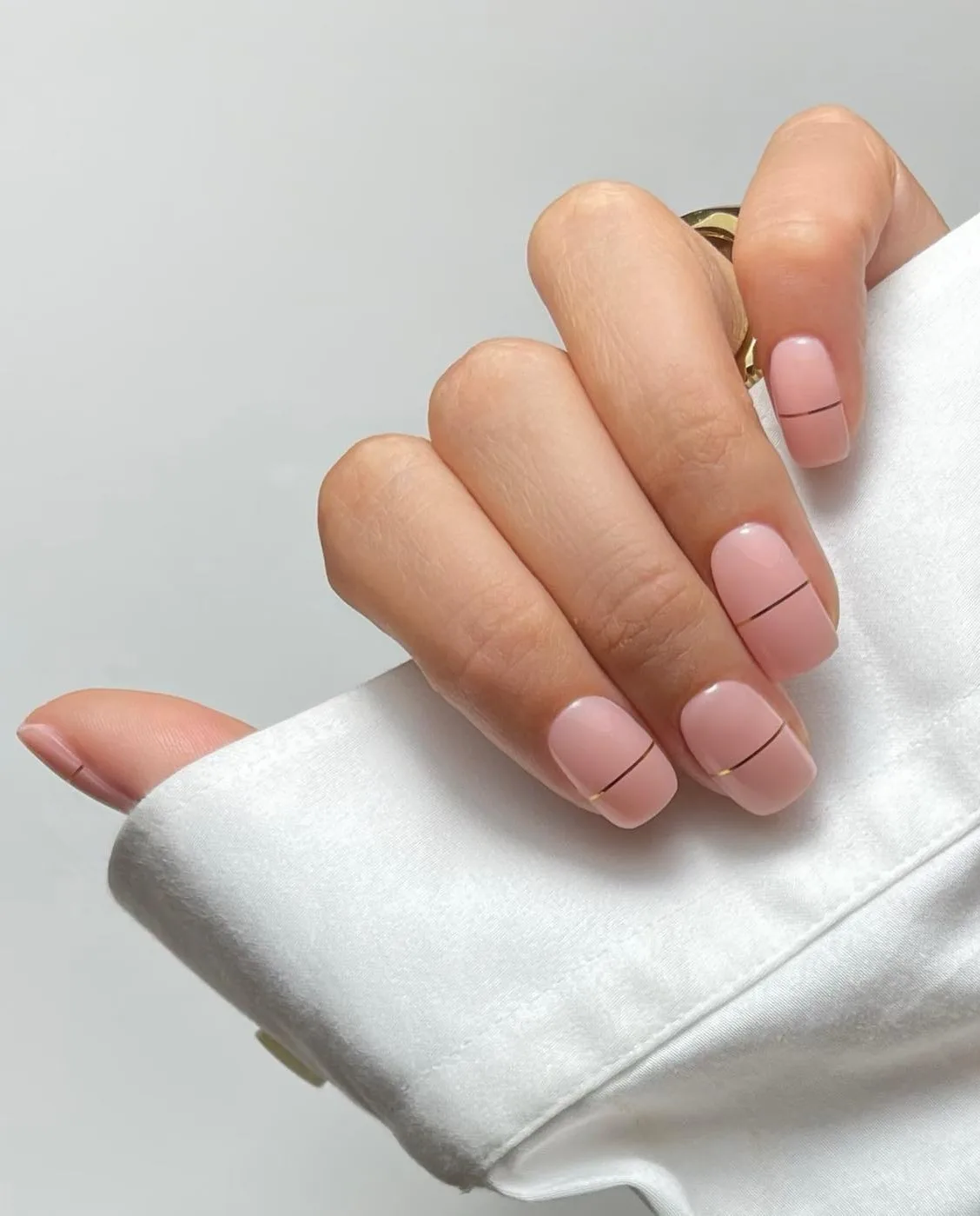 minimal winter nails in soft pink with thin gold line accents