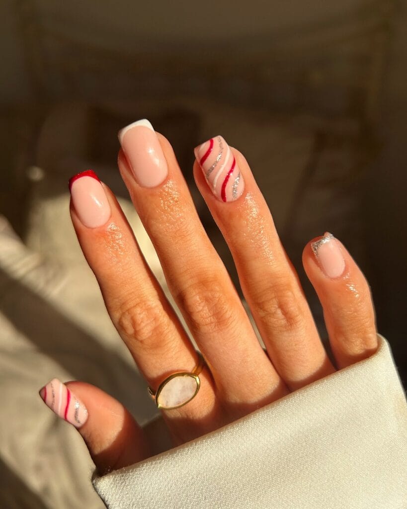 nude nails with candy cane red and silver swirls, festive Christmas French tip