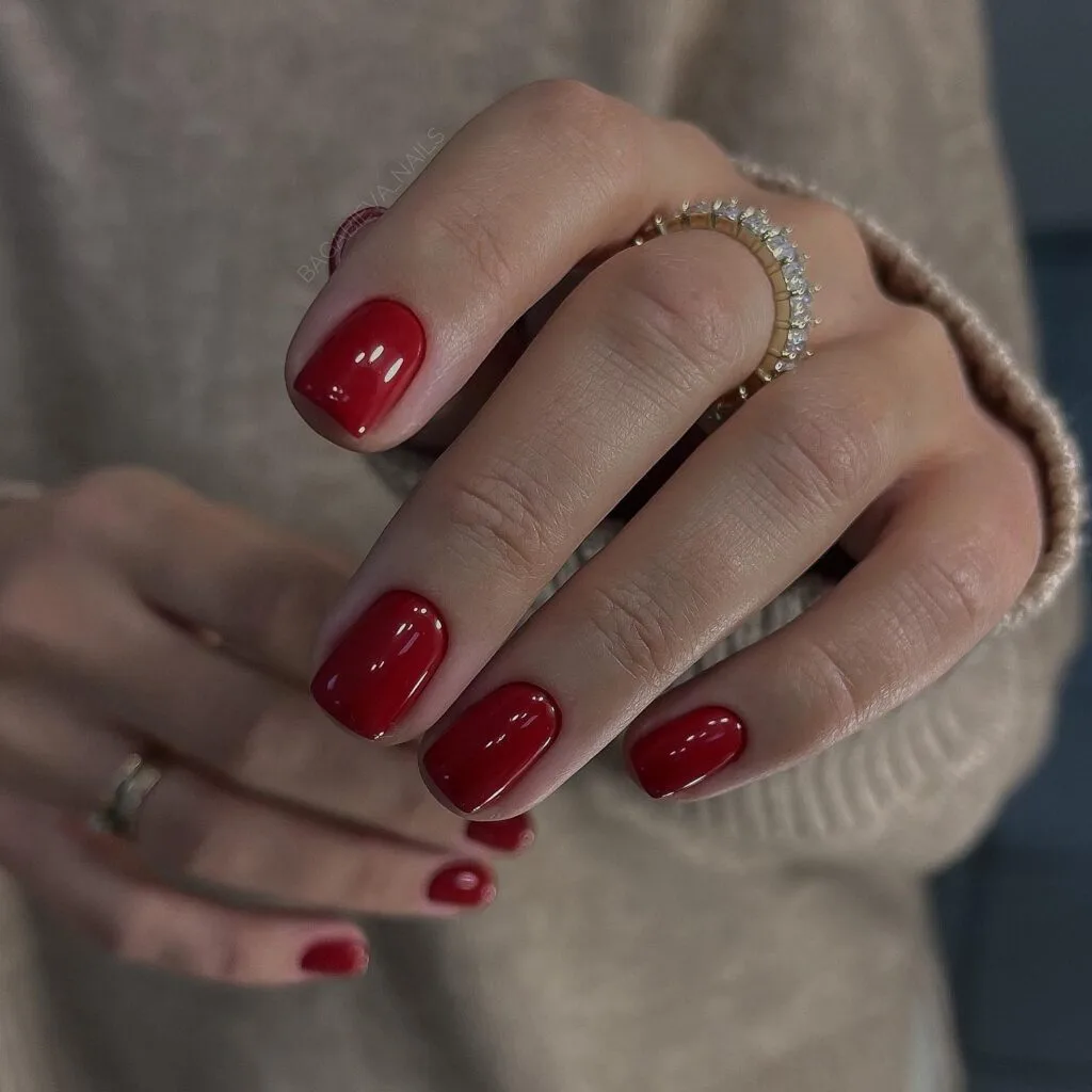 Simple winter nails in classic glossy red on short rounded nails.