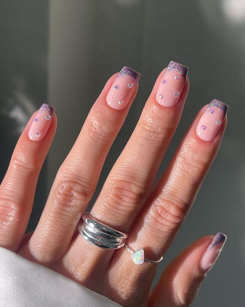 winter nails with pink base, purple glitter French tips, and tiny rhinestones