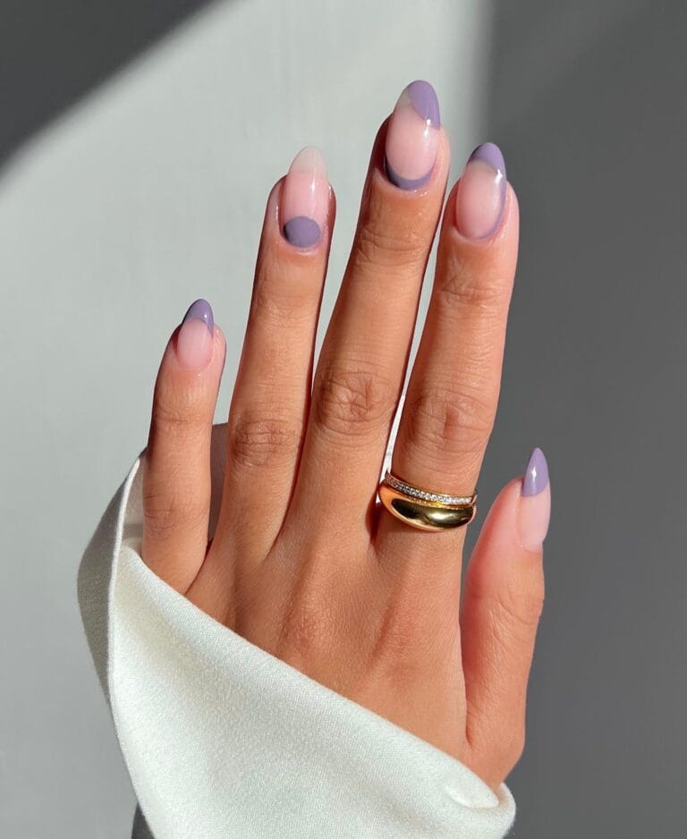 Simple winter nails with nude base, lavender French tips, and half-moon accents on almond nails.