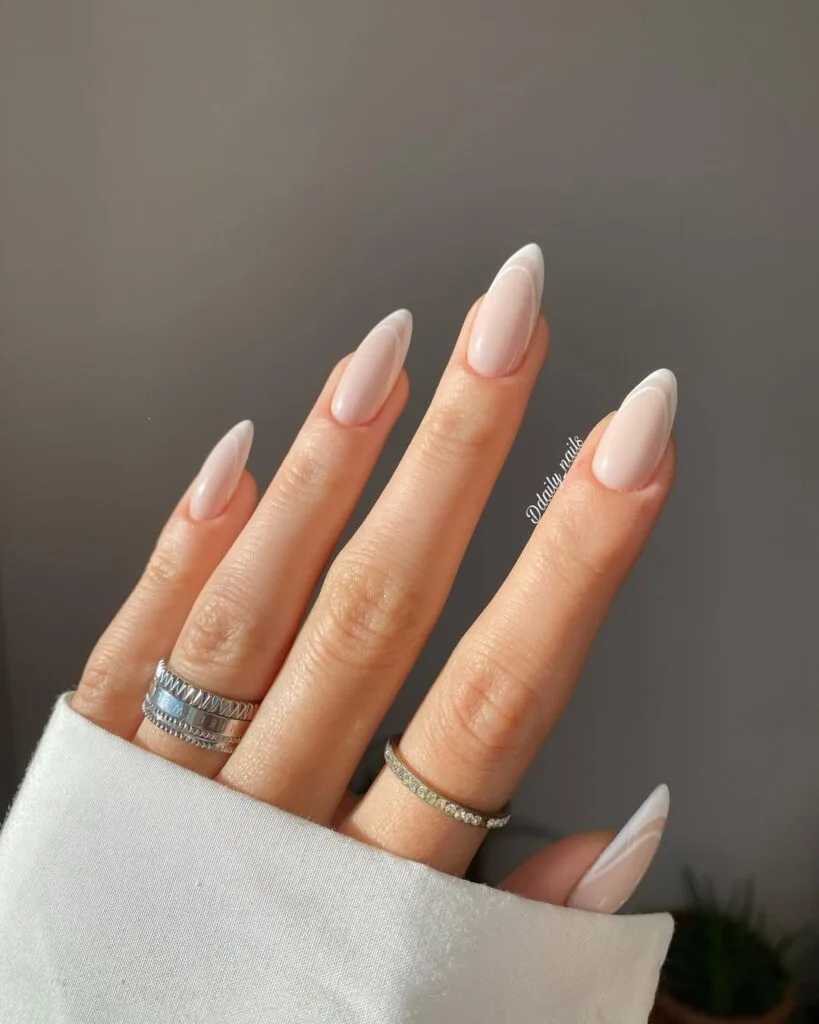 Simple winter nails with nude almond base and double-line white French tips.