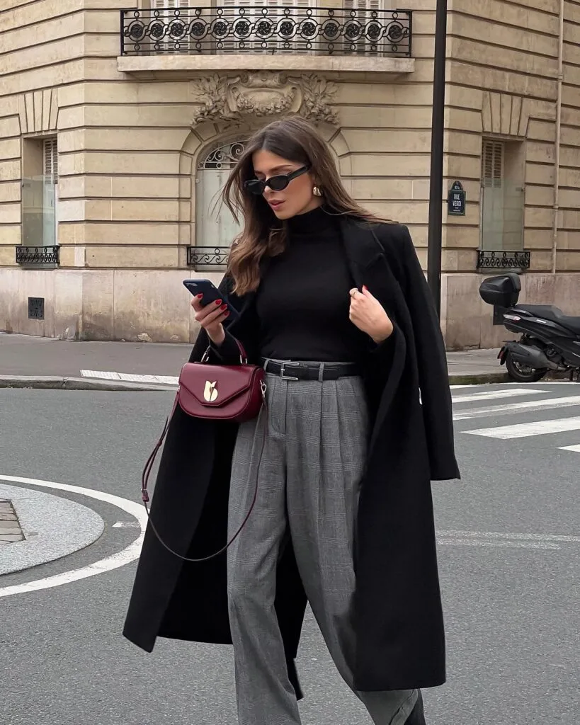 winter work outfit with black coat, black turtleneck, grey plaid trousers, burgundy handbag, black belt