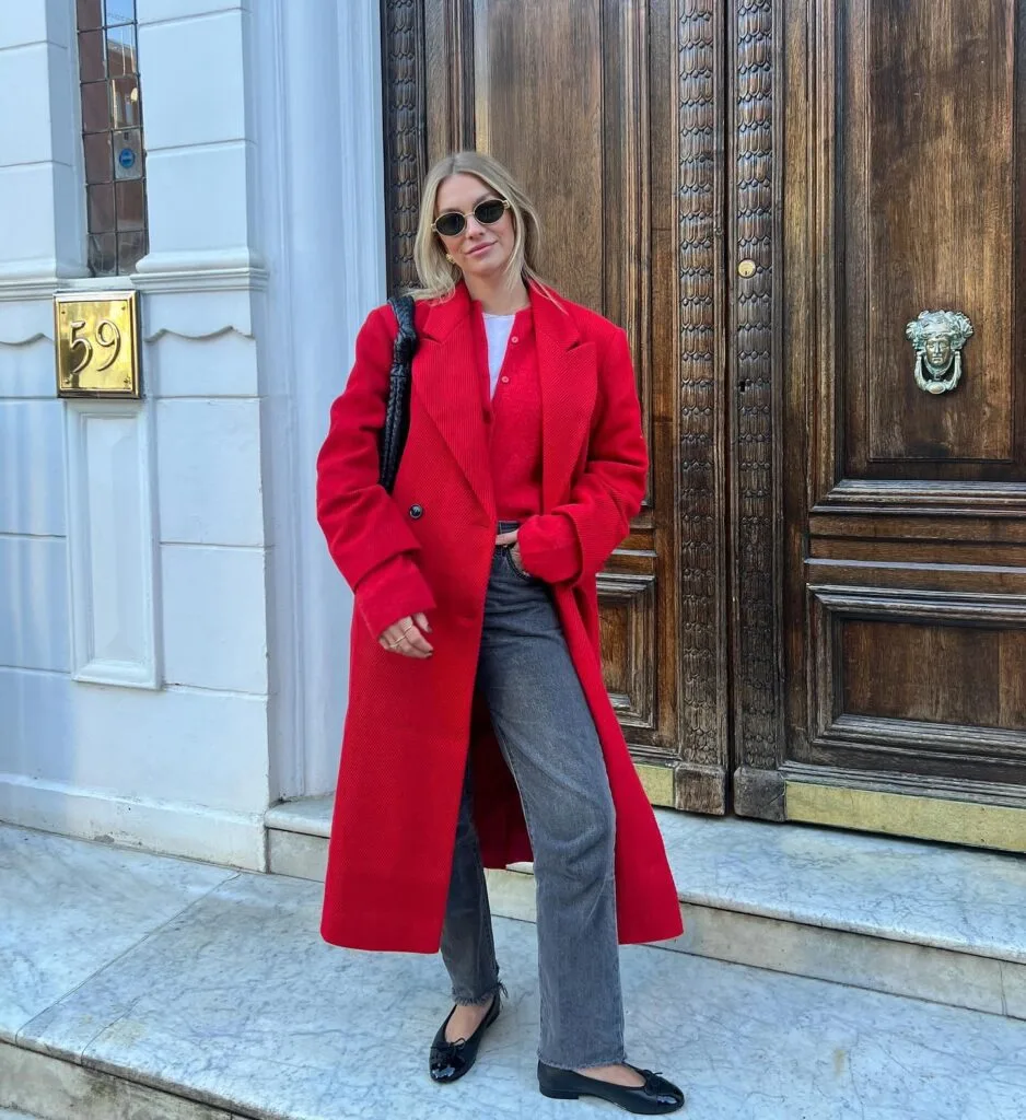 Bright red coat and cardigan with grey jeans and black flats—bold casual winter outfits for cold days.
