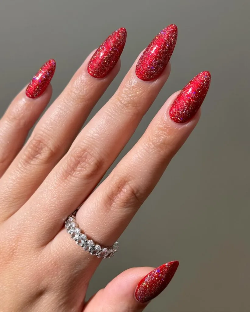 long almond nails painted with bright red holographic glitter, Christmas nails