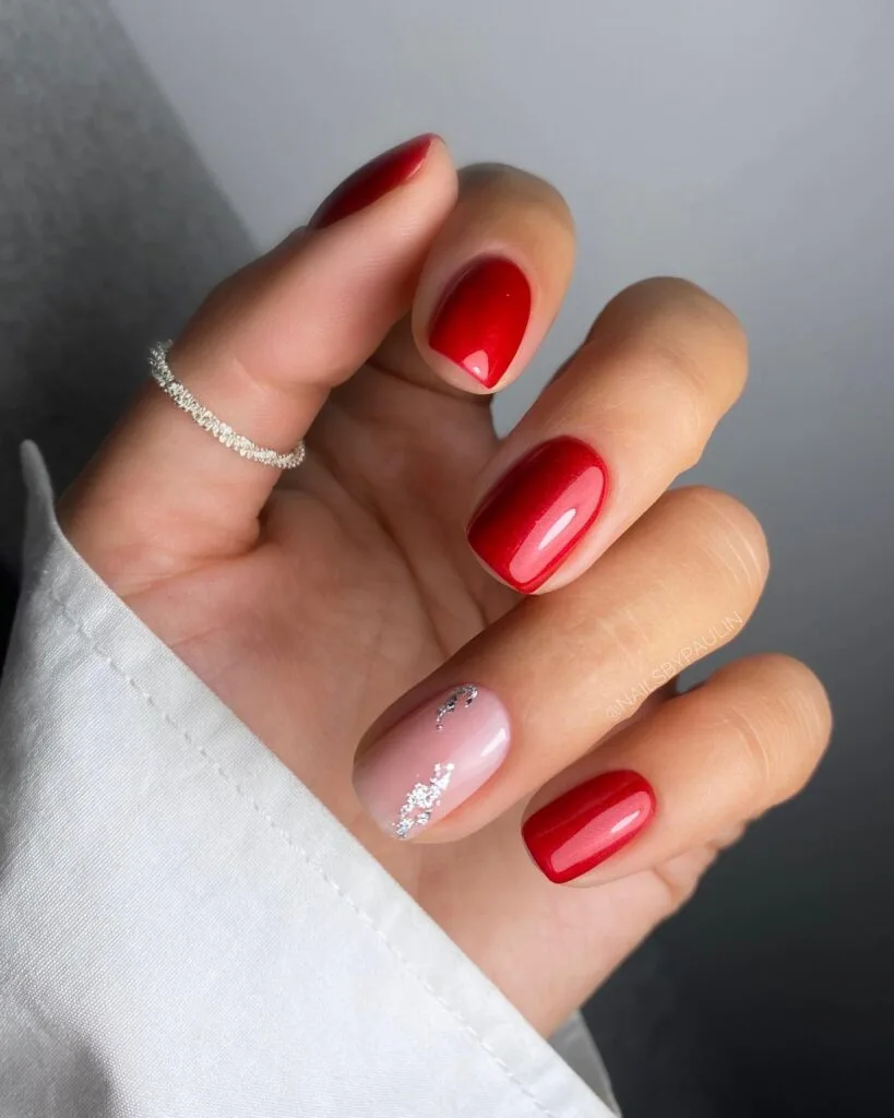 glossy red manicure and nude accent nail with silver glitter; simple winter nails idea.