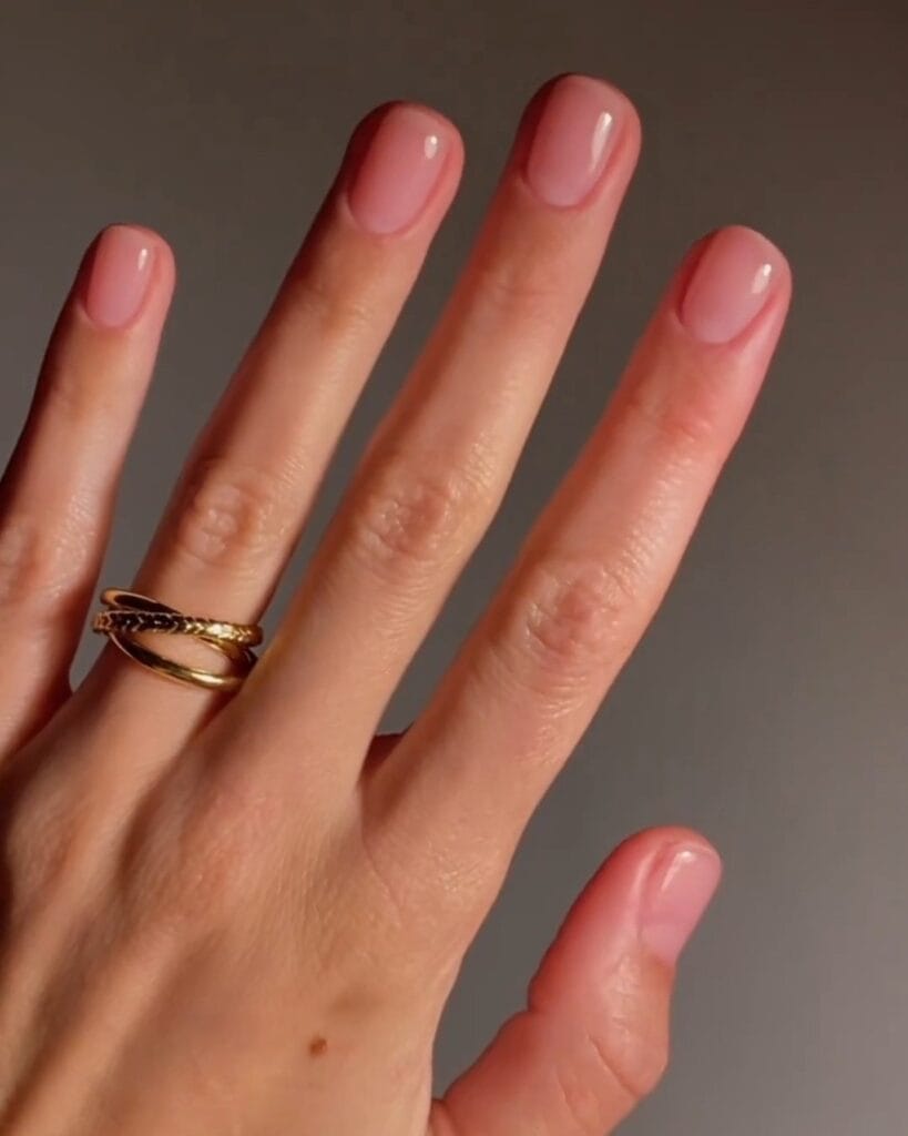 nail colors for 2026, short rounded nails in sheer pink with glossy finish and gold rings