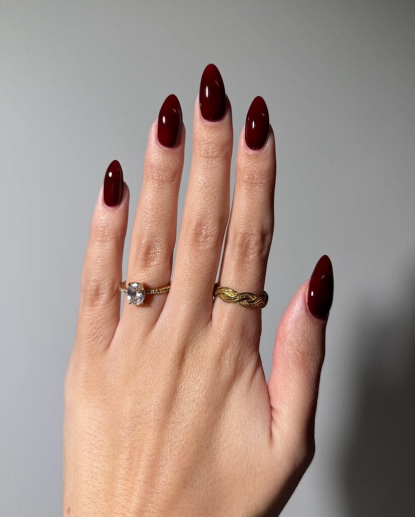 trendy nails in deep burgundy brown, almond shape with glossy finish and gold rings