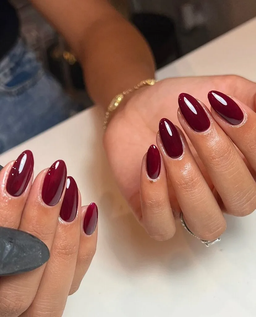 chocolate cherry almond nails with glossy finish, pearl bracelet, burgundy red shade