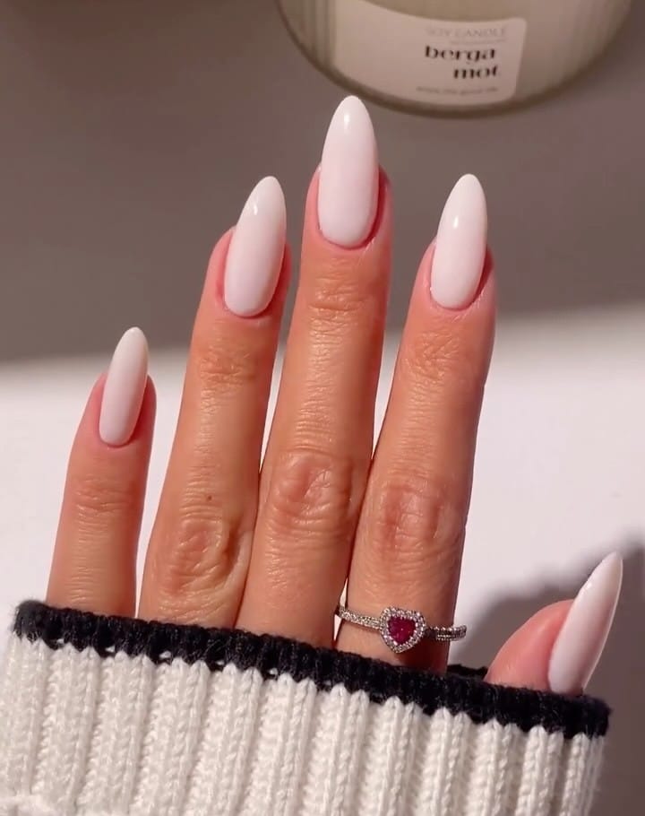 foam white almond nails with glossy finish, red heart ring, cream sweater