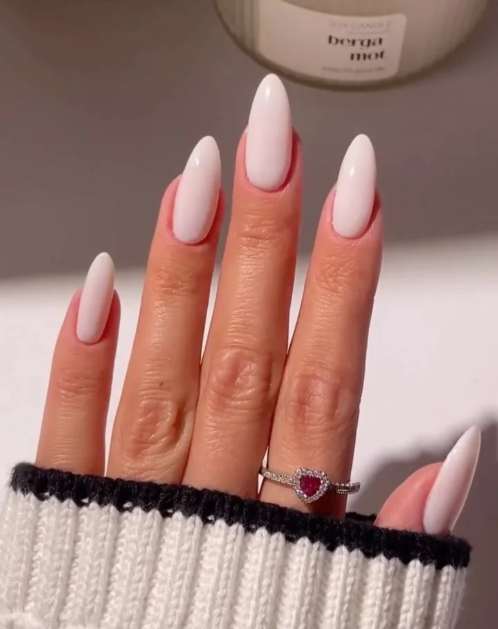 foam white almond nails with glossy finish, red heart ring, cream sweater