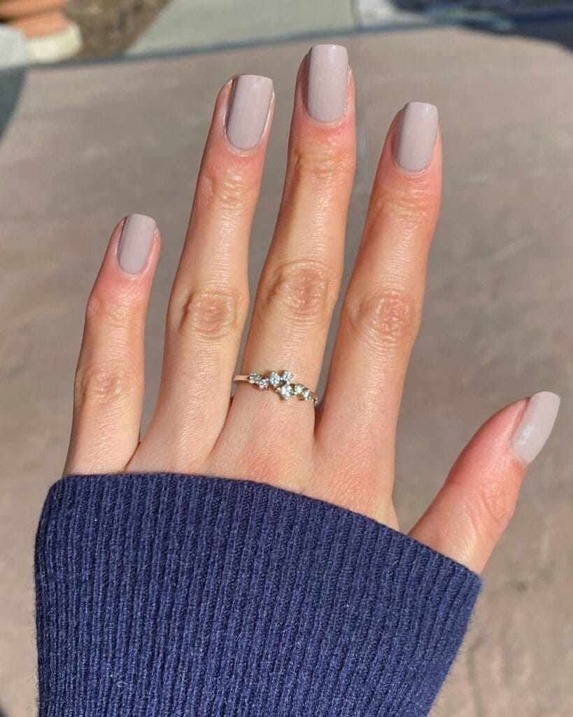 trendy nails in oyster gray, short square shape with diamond ring and navy sweater