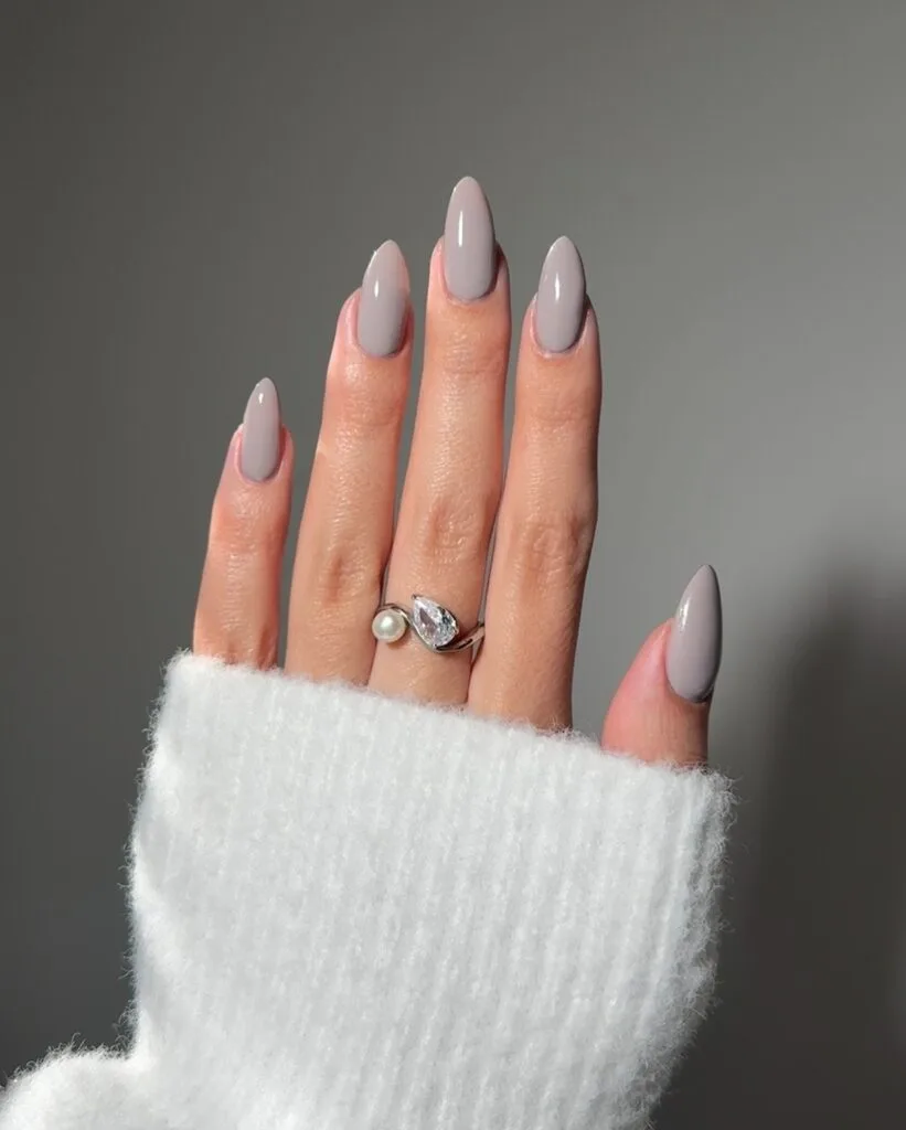 warm taupe almond nails with glossy finish, pearl and diamond ring, white sweater