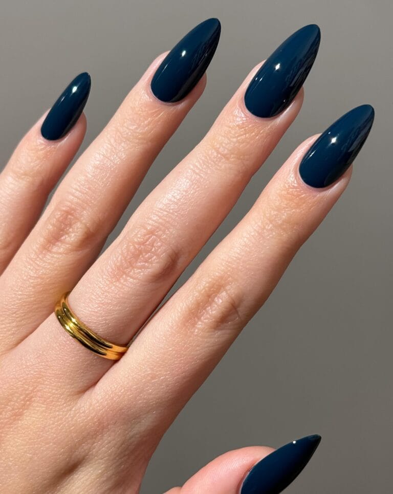 trendy nails in glossy midnight blue, almond shape with gold band ring