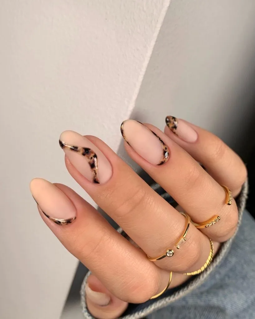 2026 nail trends, minimal tortoiseshell swirls and outlines on nude almond nails with gold rings