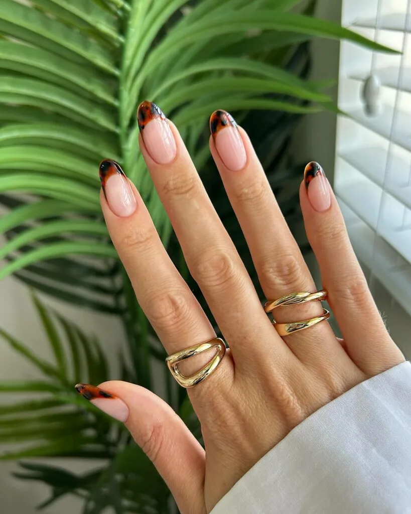 2026 nail trends, tortoiseshell tips on almond nails with nude base and gold statement rings