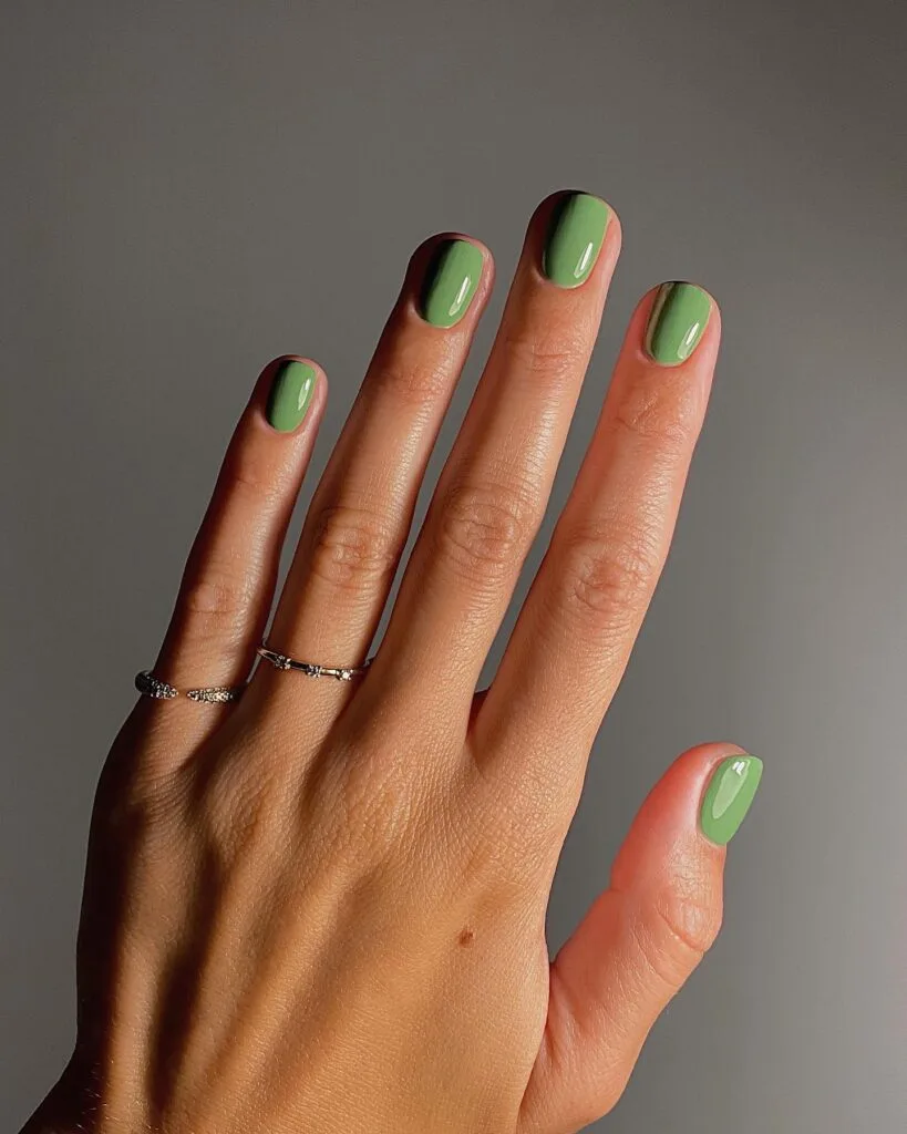 trendy nails in muted olive green, short rounded shape with silver rings