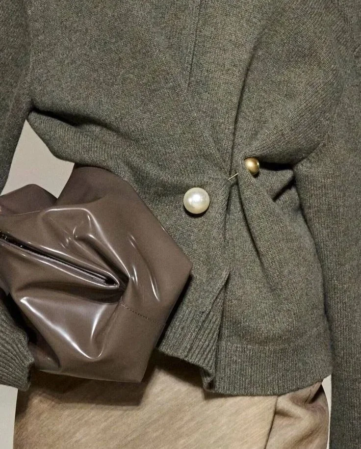 2026 fashion trends, grey cardigan with pearl and gold brooches, brown leather clutch bag