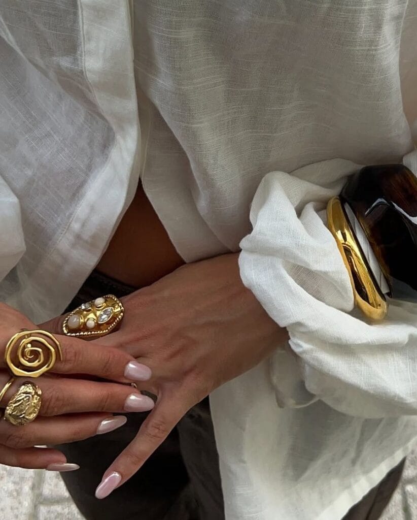 2026 fashion trends, chunky gold statement rings stacked on fingers, gold and tortoiseshell cuff bracelets