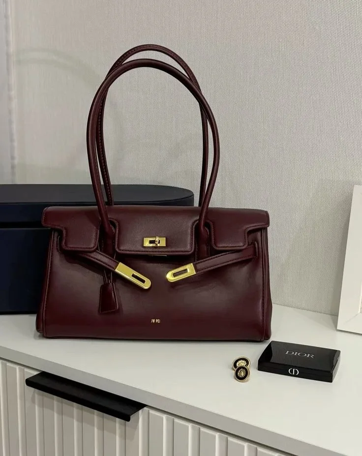 2026 fashion trends, burgundy structured leather top-handle bag with gold hardware, sculptured handbags
