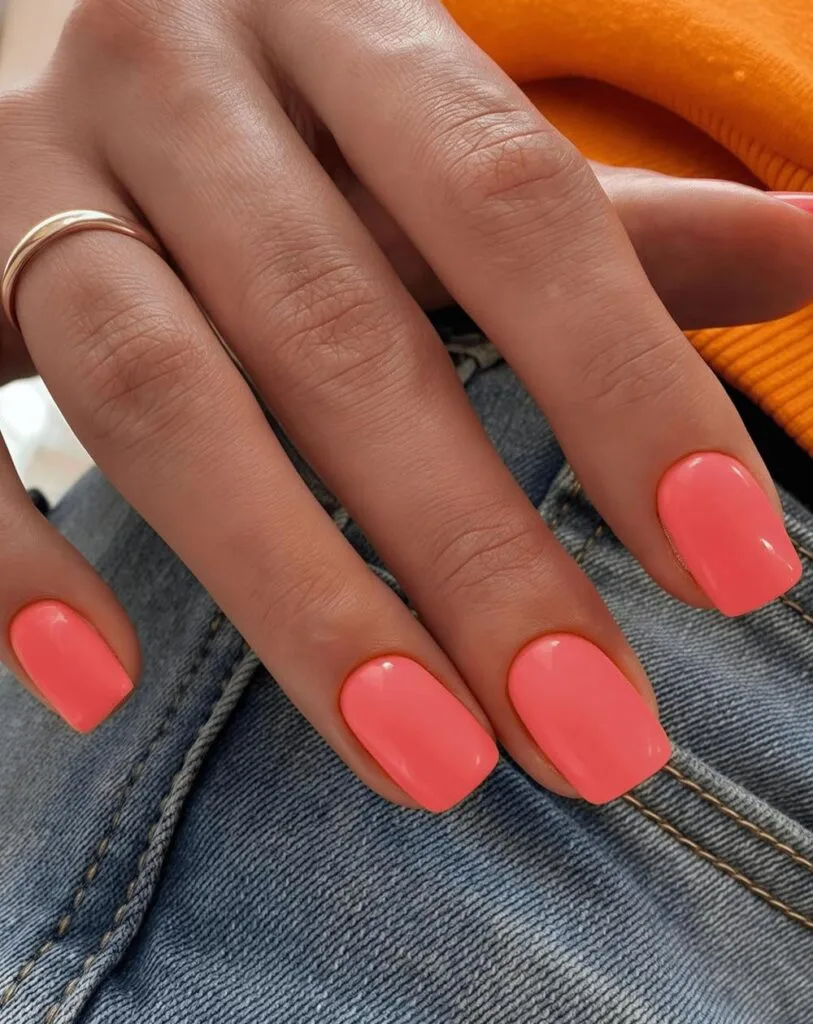 spring nail colors 2026, bright coral short square nails with gold ring, glossy finish